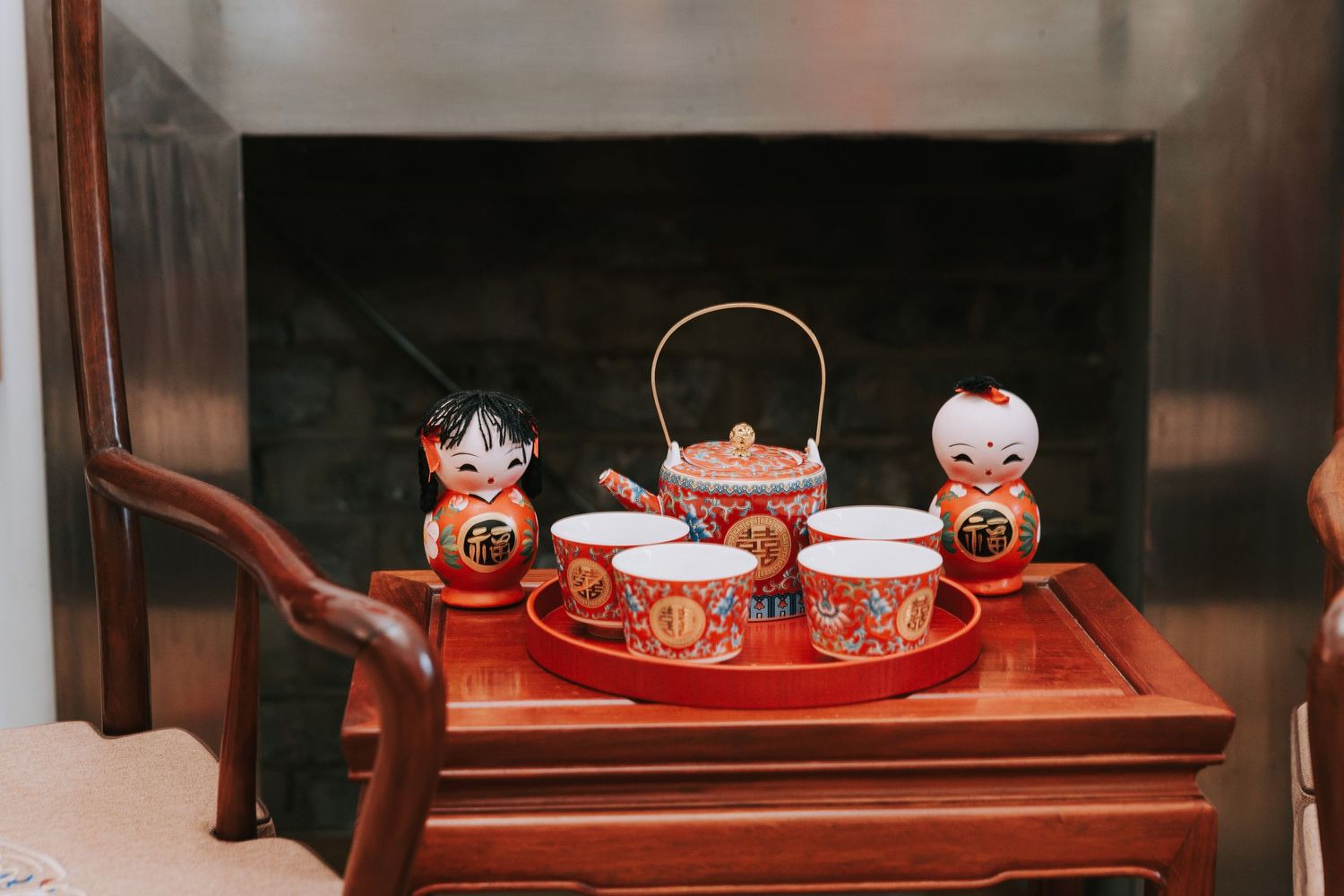 Traditional Chinese red tea set with teapot, cups, and decorative figurines displayed on a wooden table.