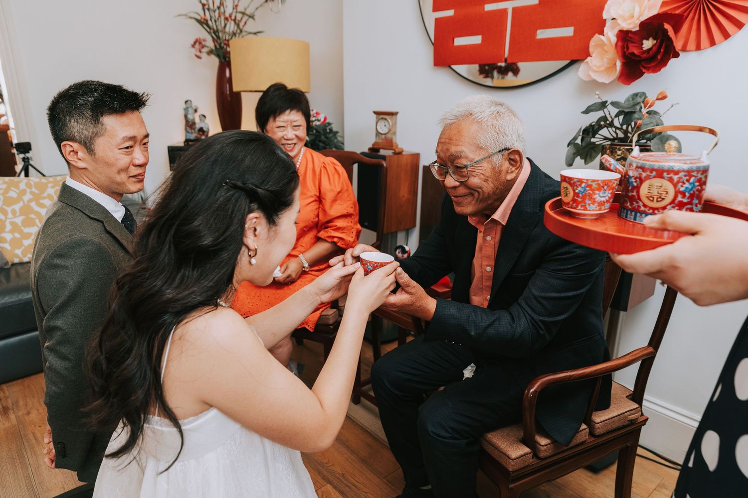 Traditional Chinese tea ceremony with bride serving elder relatives, exchanging red envelopes and gifts at a wedding.