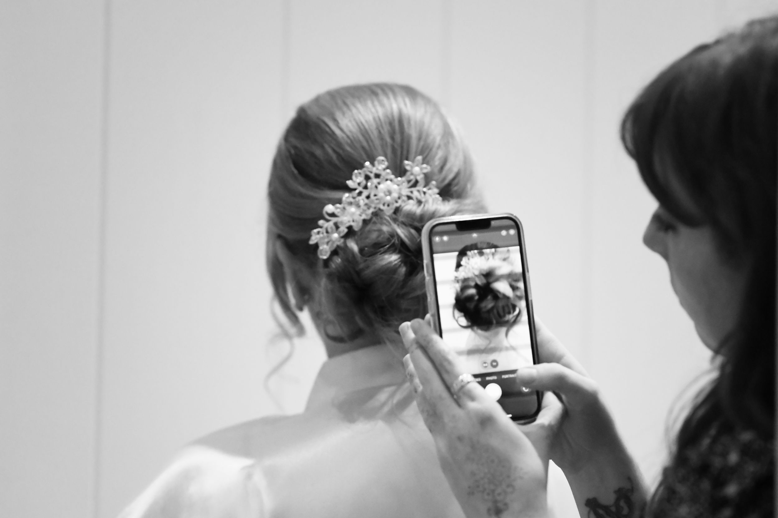 Someone taking a photo of an elegant bridal hairstyle with a mobile phone.