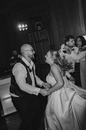Bride and groom share a joyful dance together in black and white photo at wedding reception.