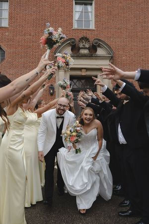 Bride and groom exit through a joyful tunnel of raised hands formed by their wedding party.