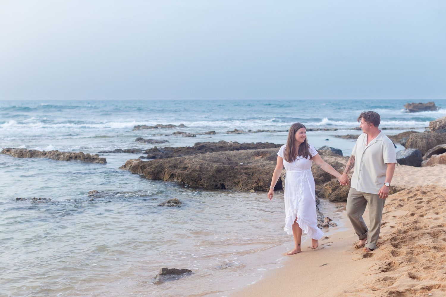 Couples portrait walking along the beach at Balneario del Escambrón in Old San Juan, Puerto Rico.