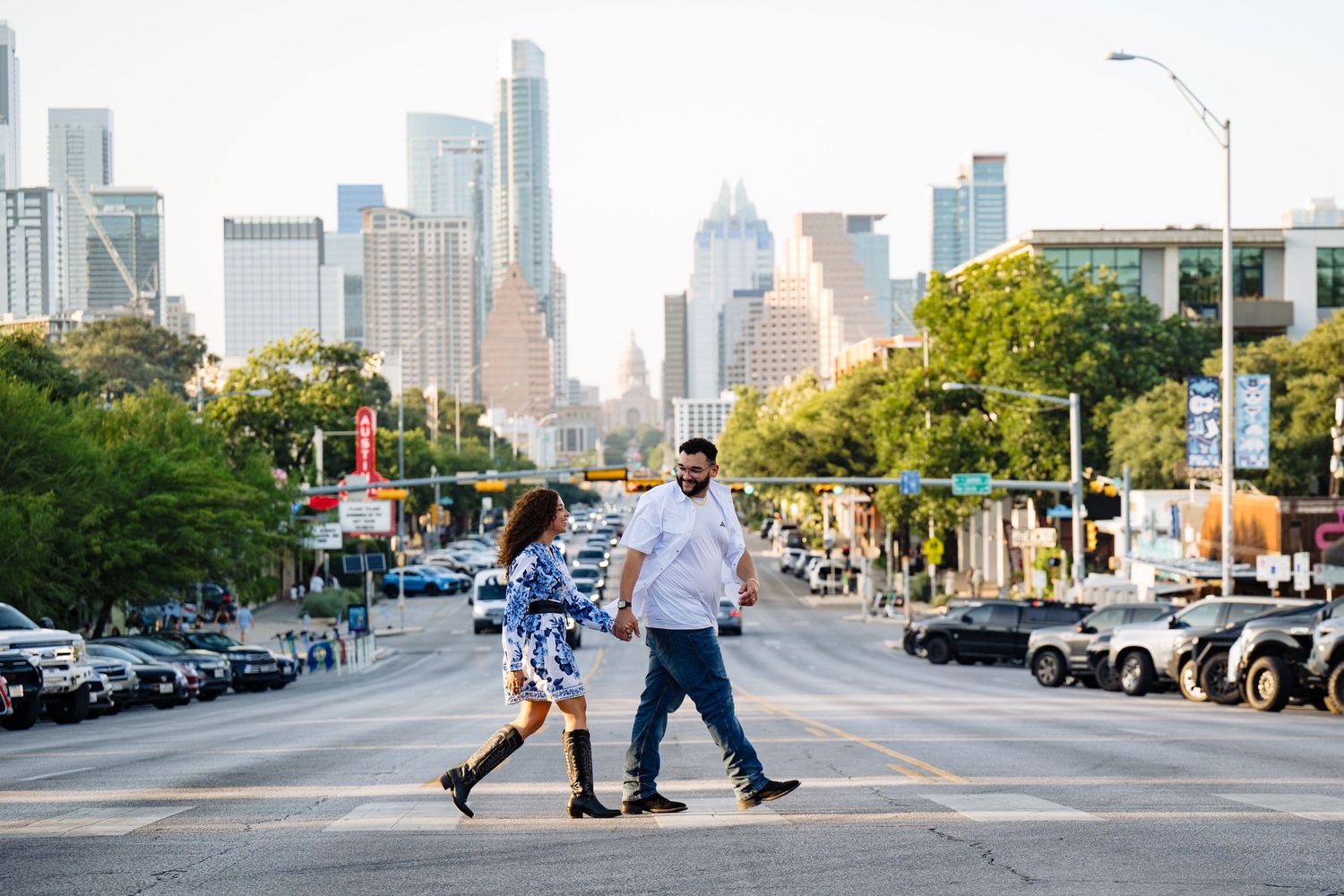 Couple crossing a street in Austin, Texas with a stunning city skyline backdrop on a sunny day.