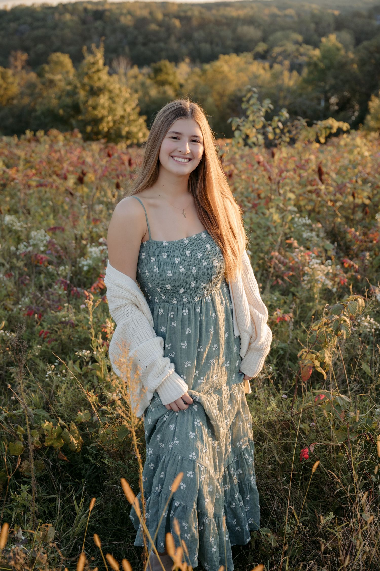 teenage girl stands alone for portraits in tall grasses during sunset for fall minis in hudson wisconsin
