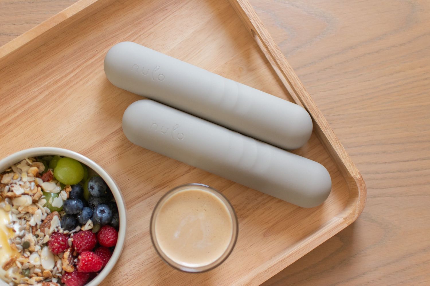 Close-up lifestyle product photograph of Nulo home fitness accessories with a breakfast bowl on a tray.