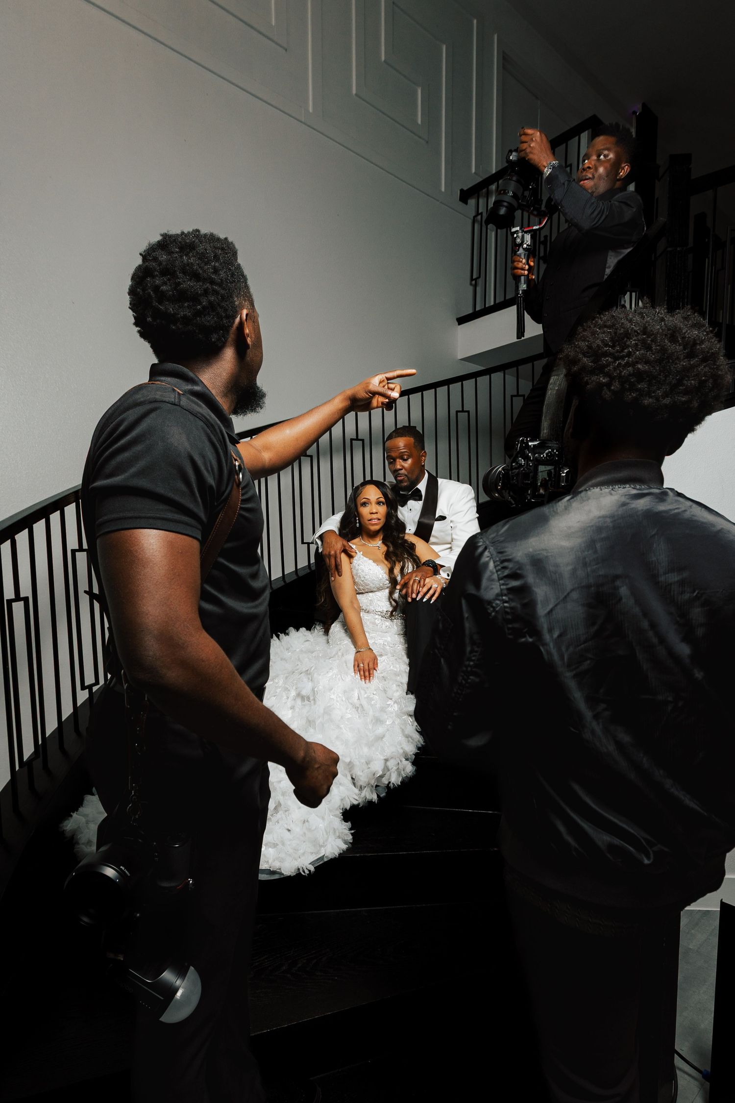 Wedding couple poses on staircase while photographers and videographers capture their special moment.