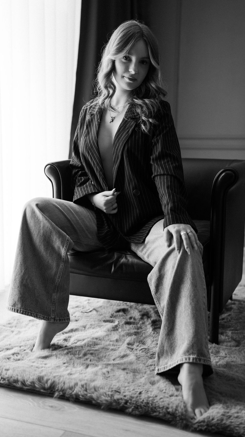 Elegantes Boudoir-Porträt einer Frau im Blazer mit zeitloser Schwarz-Weiß-Ästhetik.