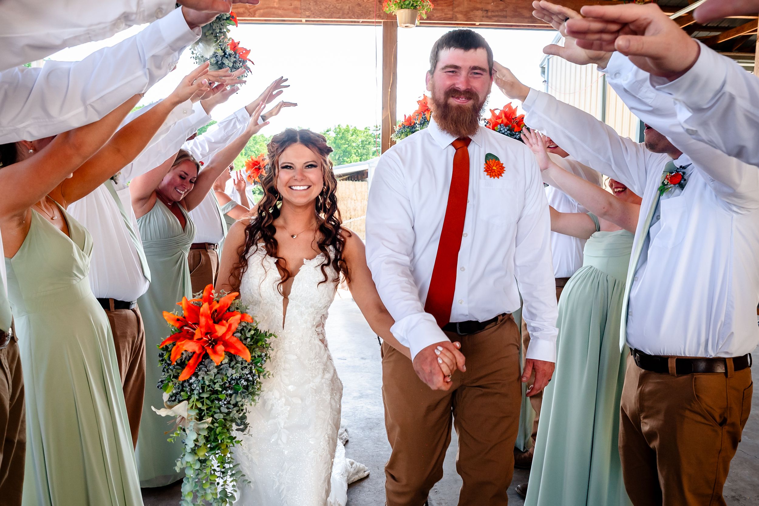 Bride and groom exit wedding ceremony holding hands as guests celebrate with raised hands.