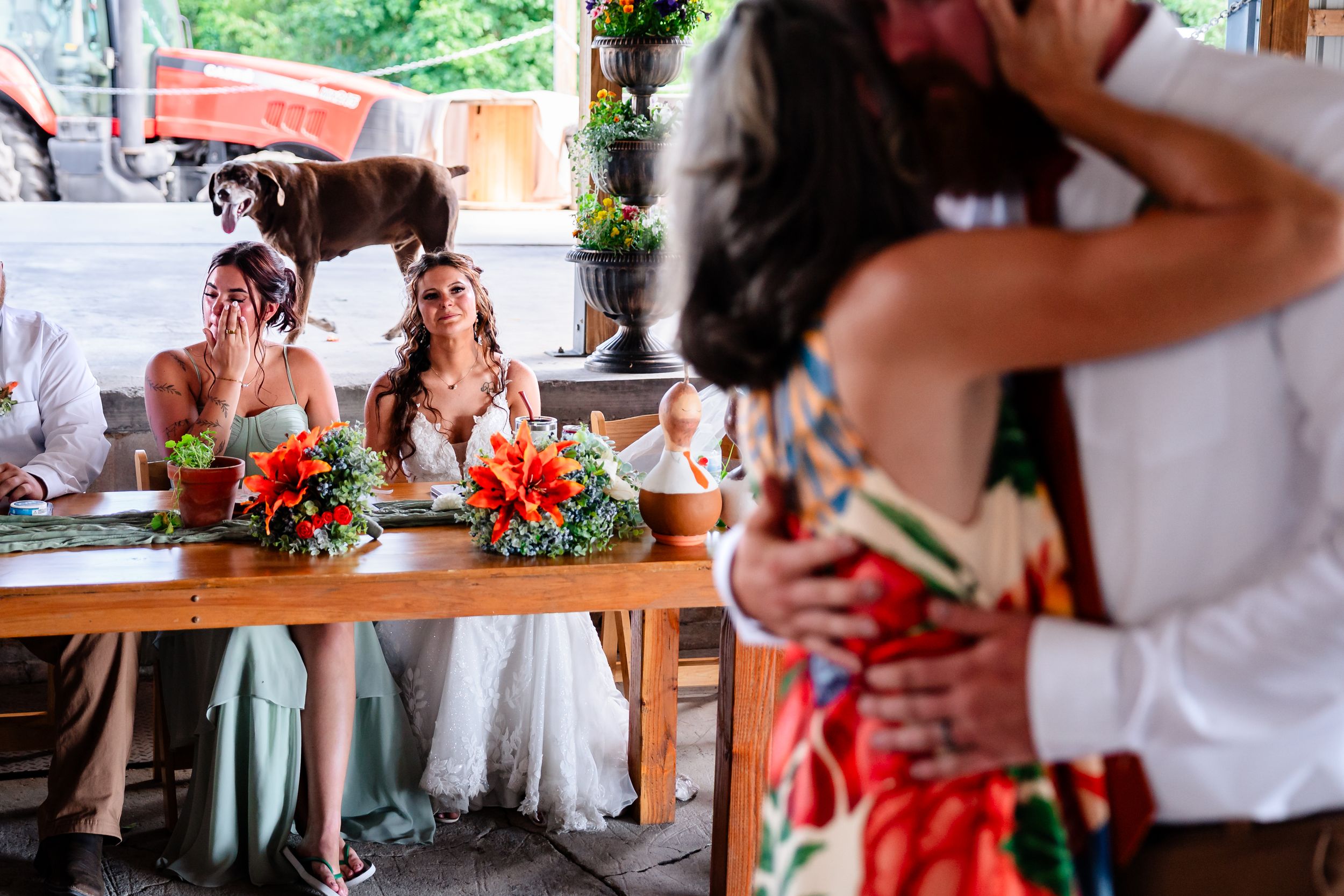 A couple shares a romantic dance while bridesmaids watch emotionally at a colorful outdoor wedding reception.
