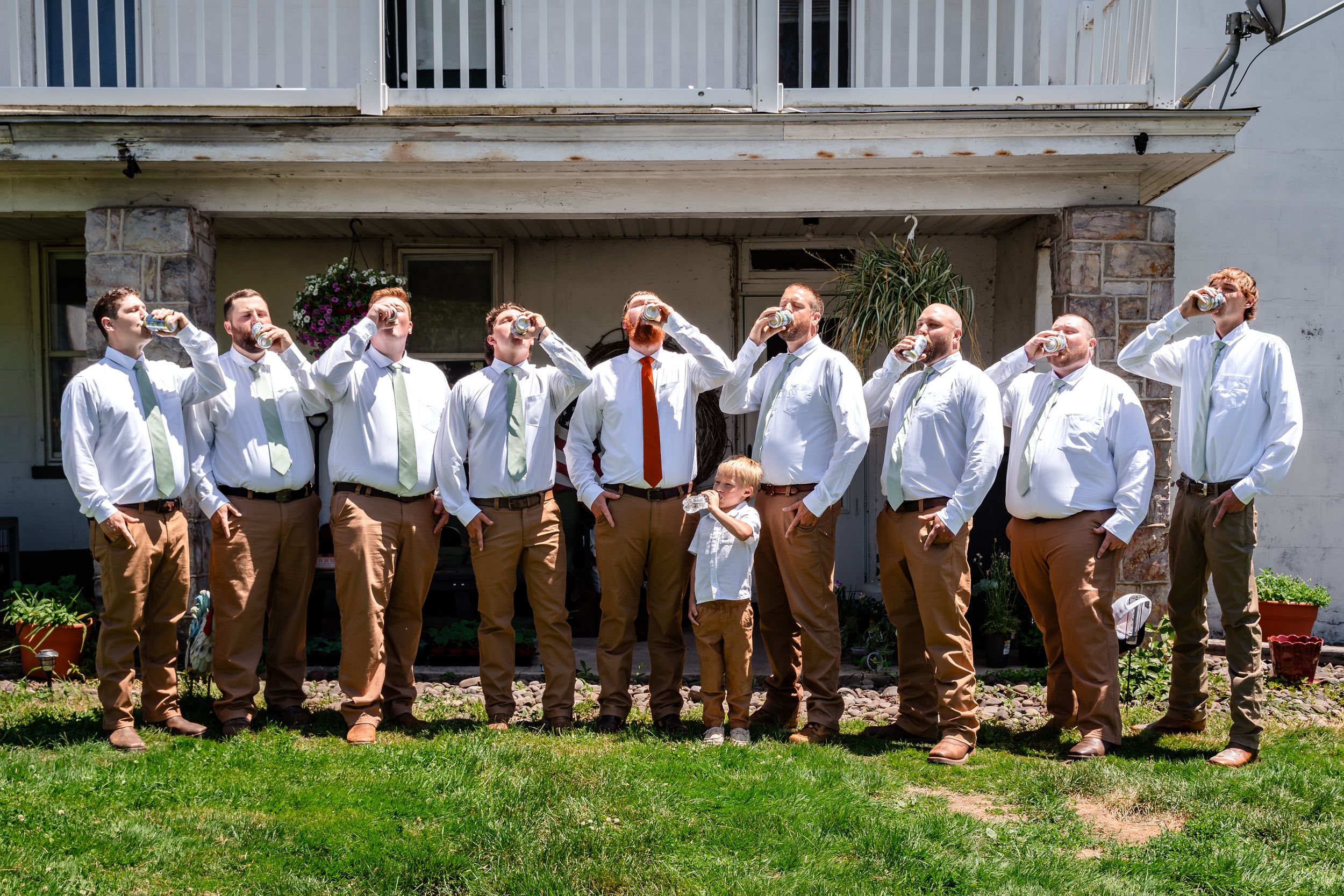 Groomsmen and groom in white shirts and khaki pants take a shot together outside before the wedding ceremony.
