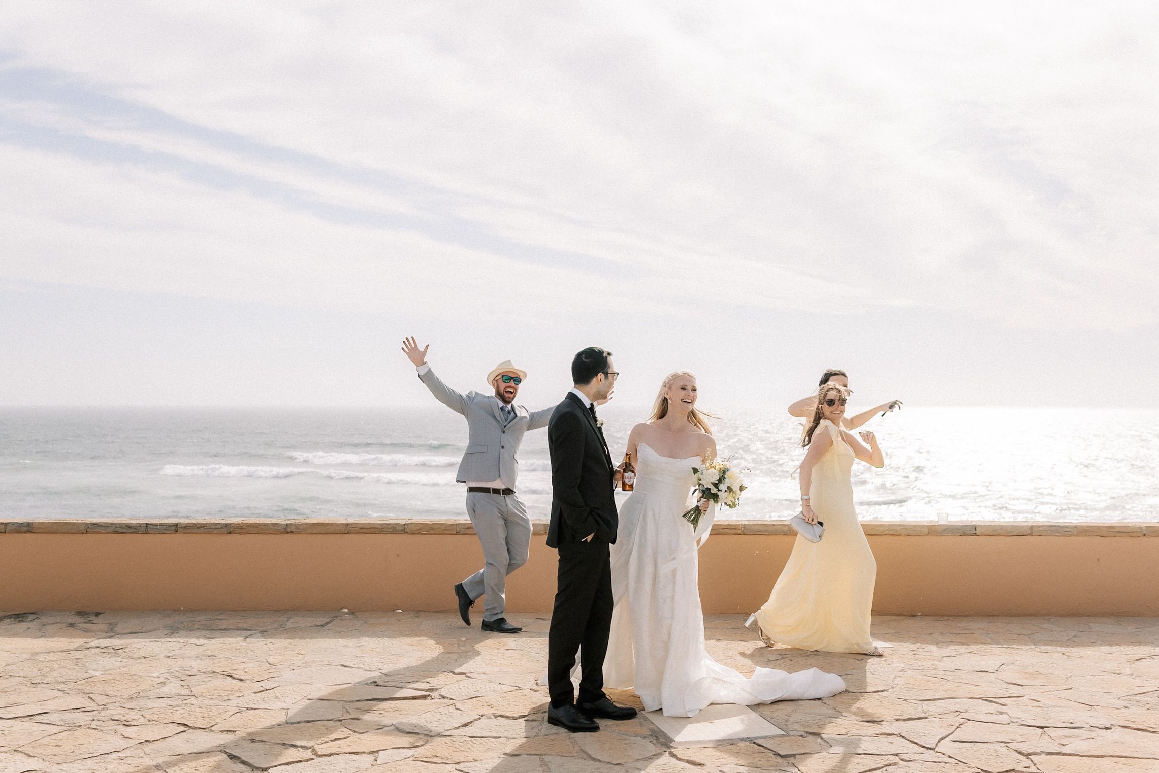 Bride, groom and bridal party celebrating together after the oceanfront wedding ceremony.