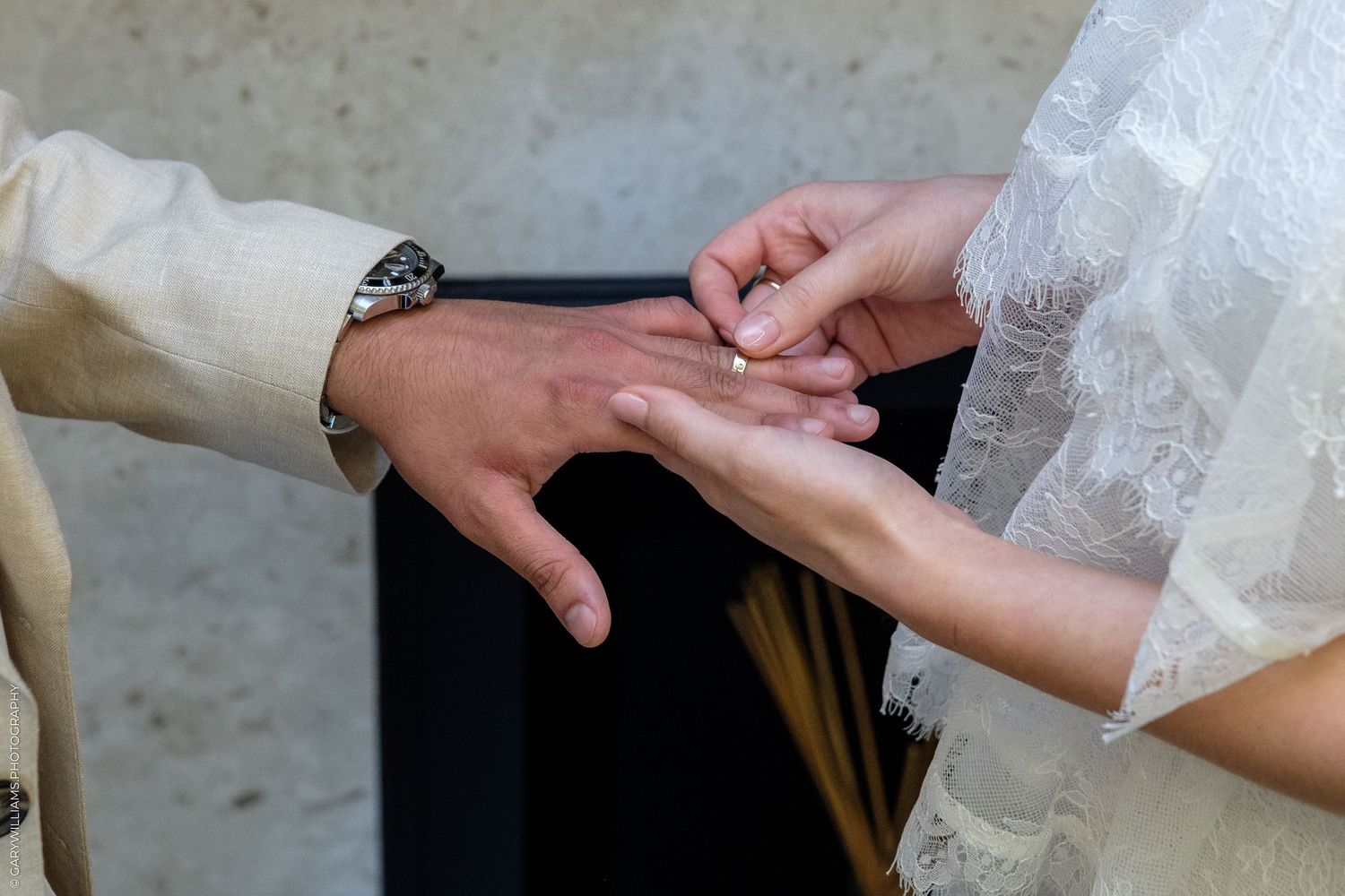 Bride placing a wedding ring on groom's finger during a wedding ceremony, close-up of hands.