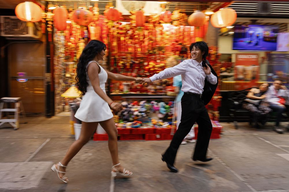 Two women dancing joyfully on a vibrant street adorned with red lanterns and colorful decorations in Chinatown.