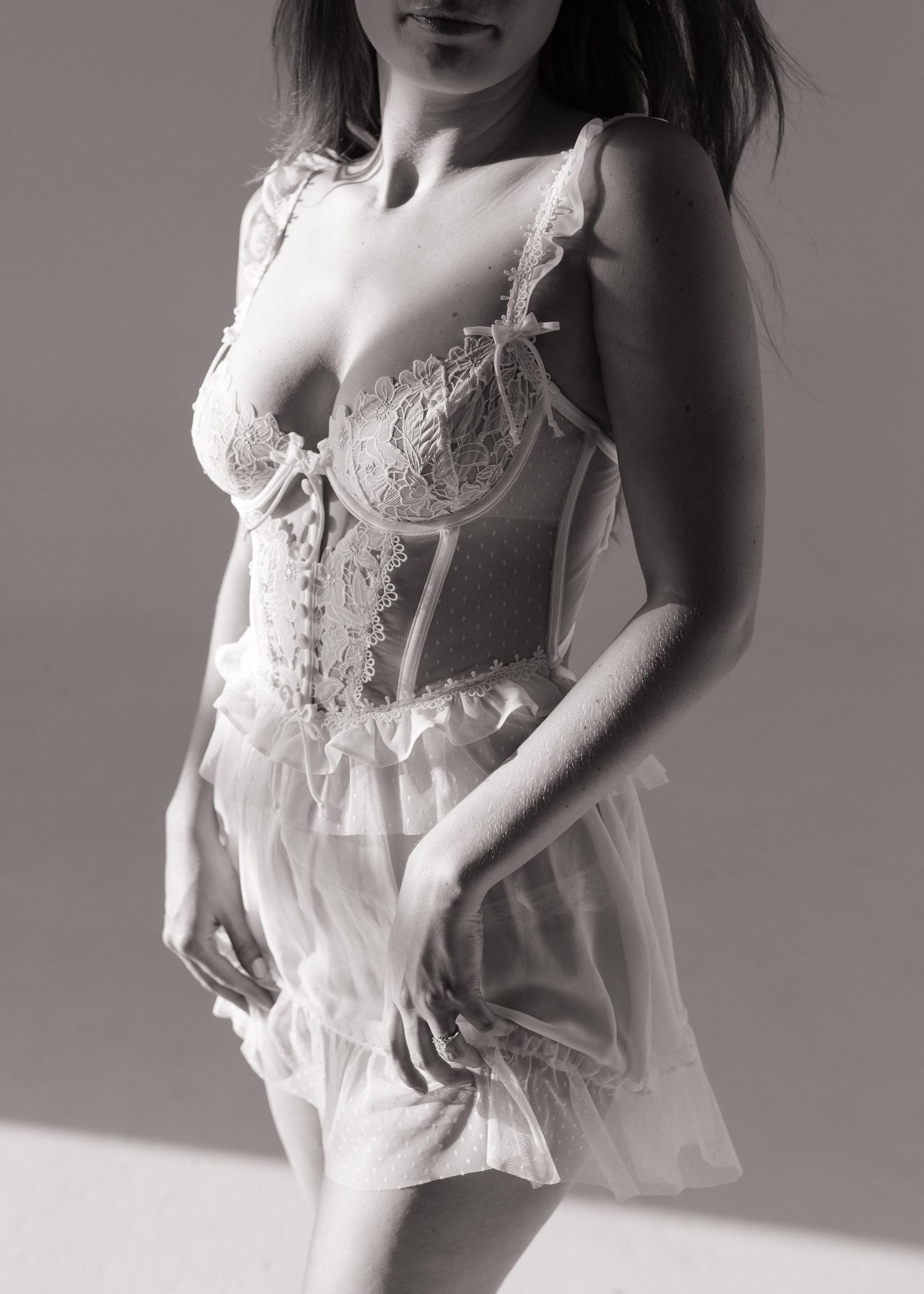 Woman in white lace corset and sheer ruffled skirt, elegant bridal lingerie set, black and white photo. Sacramento, California.