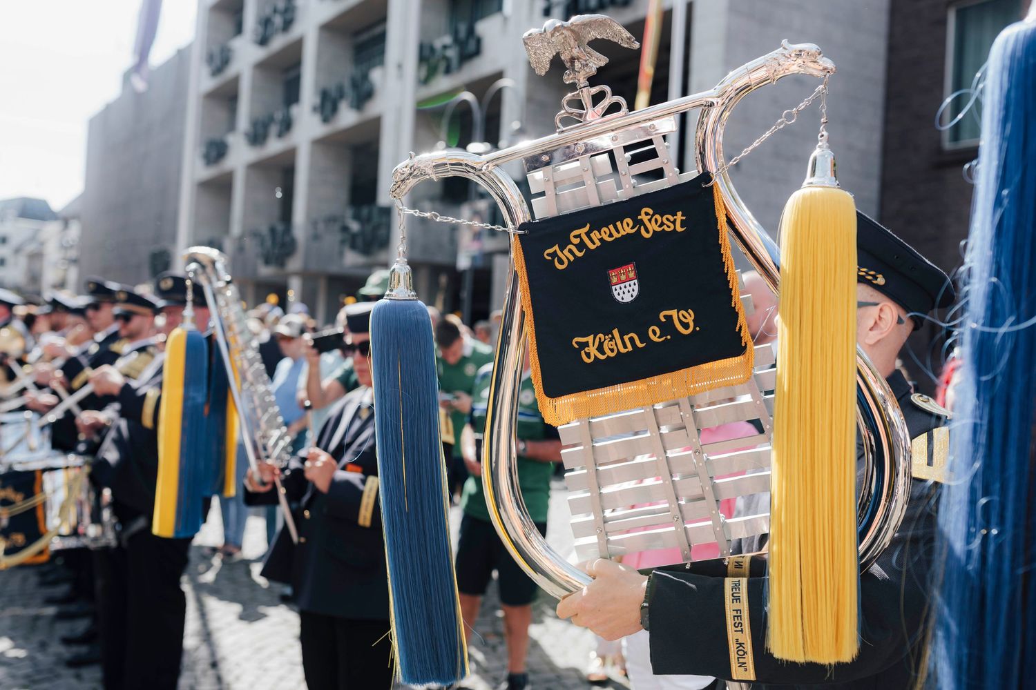 Decorated lyre instrument with blue and yellow tassels at a German brass band parade festival.