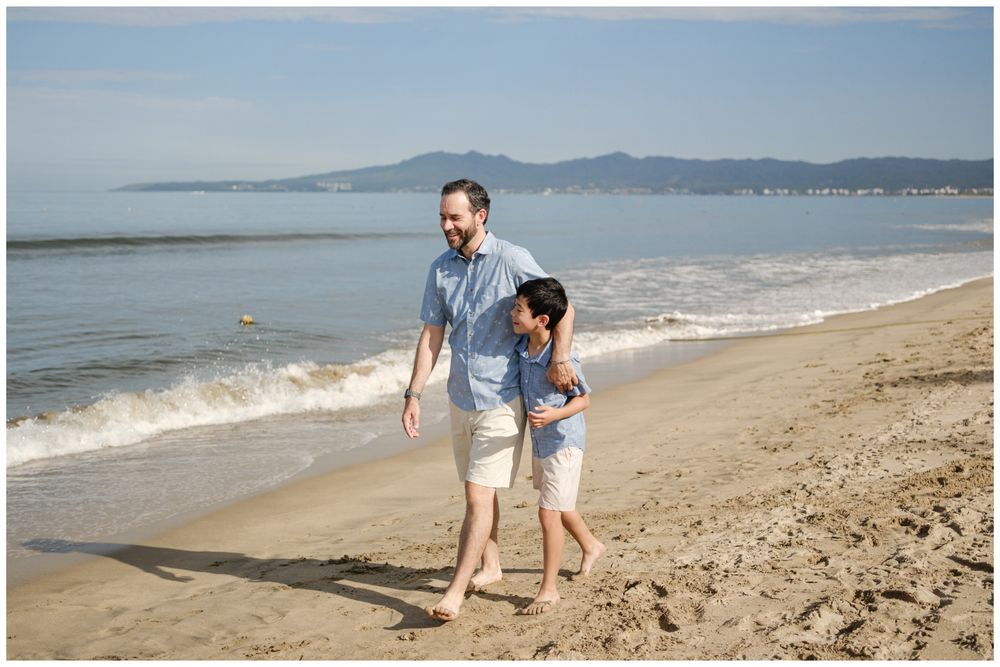 Father and child walking barefoot on Sayulita beach, Mexico with ocean waves and mountain views, candid family photography Riviera Nayarit