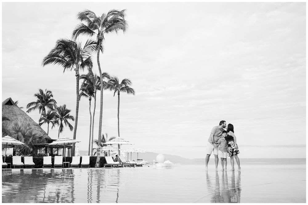 Black and white couple embracing at infinity pool in Punta Mita, Mexico resort with ocean views, luxury family photography setting.