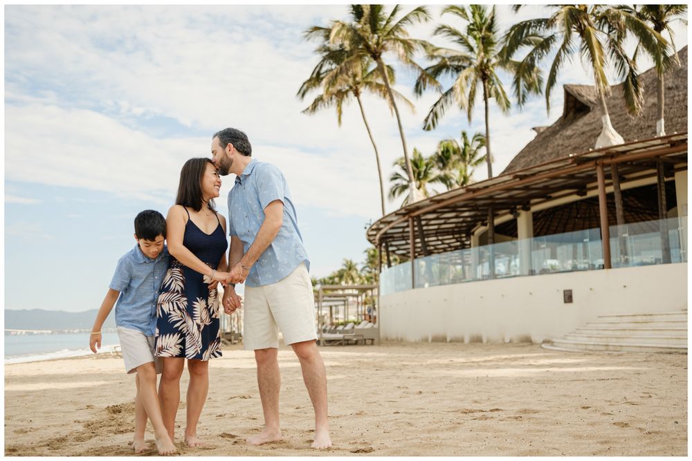 Family of three enjoying a sunny beach day in Sayulita, Mexico with palm trees and tropical resort, candid family photographer.