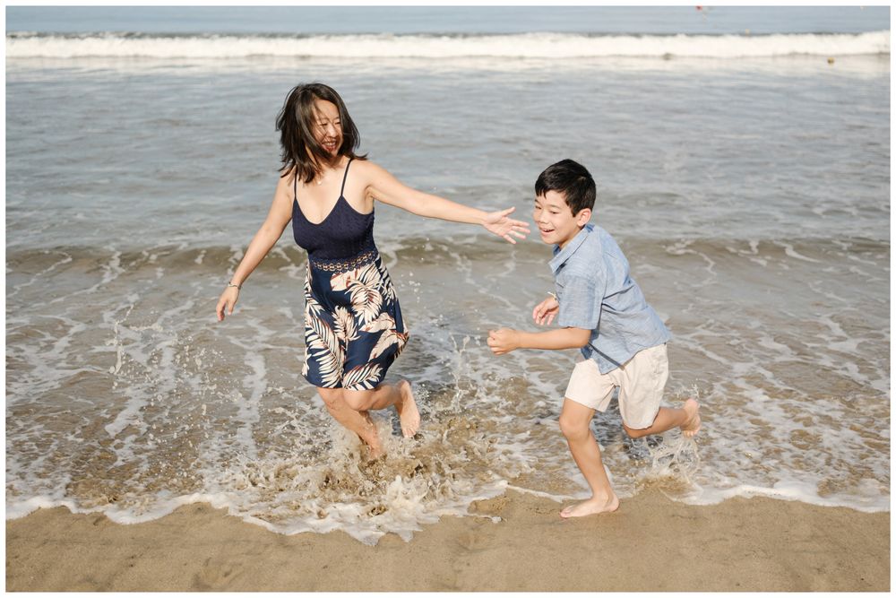 Mom and son jumping over ocean waves in Puerto Vallarta, Mexico beach family session, candid lifestyle family photography Riviera Nayarit.