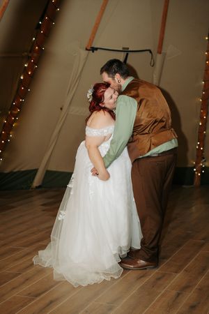 Bride and groom share a tender first dance inside a warmly lit teepee wedding venue.