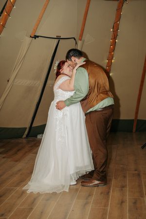 Bride and groom share a romantic kiss during their first dance inside a fairy-lit teepee.