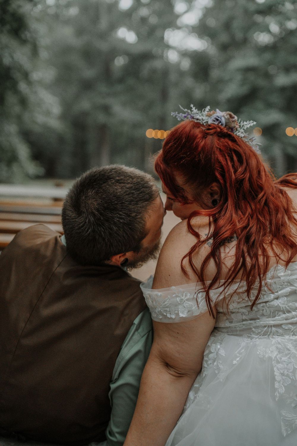 Intimate moment of bride with red hair and groom sharing a close embrace outdoors.