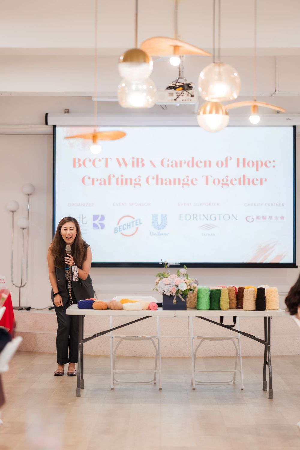 Speaker presents BCCT WiB x Garden of Hope Crafting Change Together event at a bright modern venue.