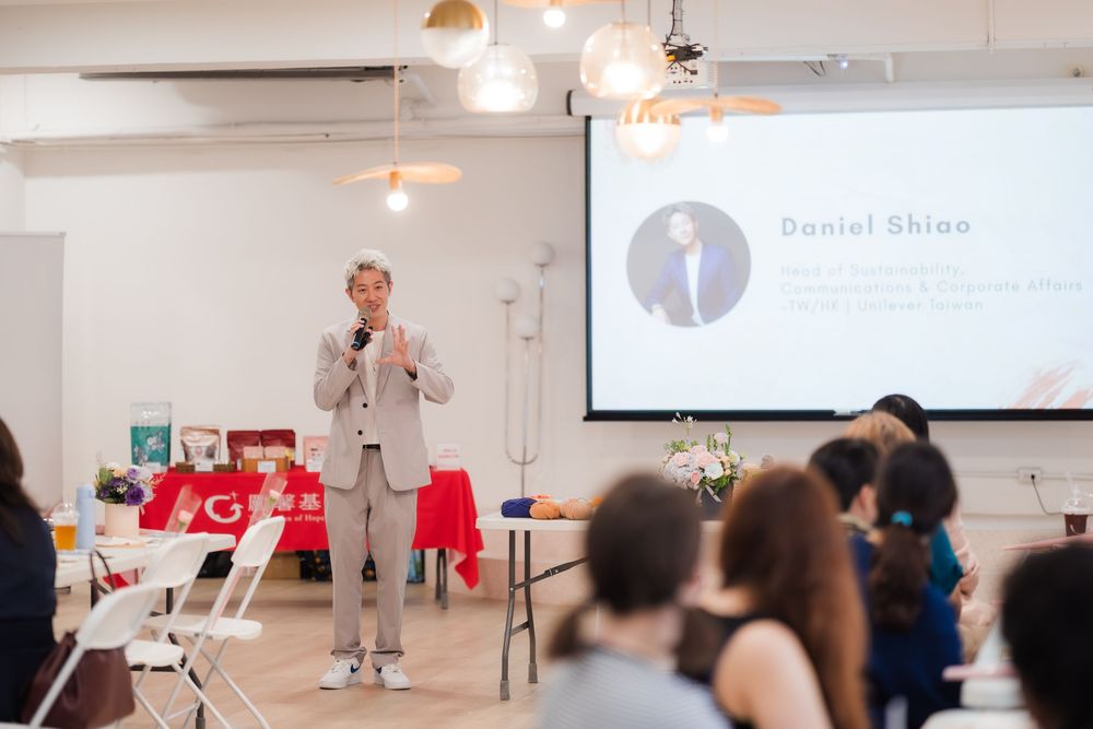 Daniel Shinn speaks at a professional event, presenting to a seated audience in a bright modern venue.