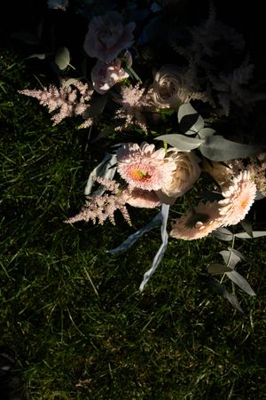 Pink and white floral bouquet arrangement lying on grass in natural lighting.