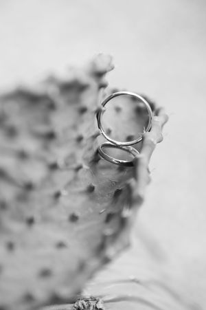Close-up black and white photo of a delicate silver ring with an adjustable open design on a textured surface.