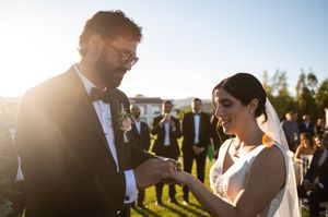 Bride and groom share a tender moment in golden sunlight during their outdoor wedding ceremony.