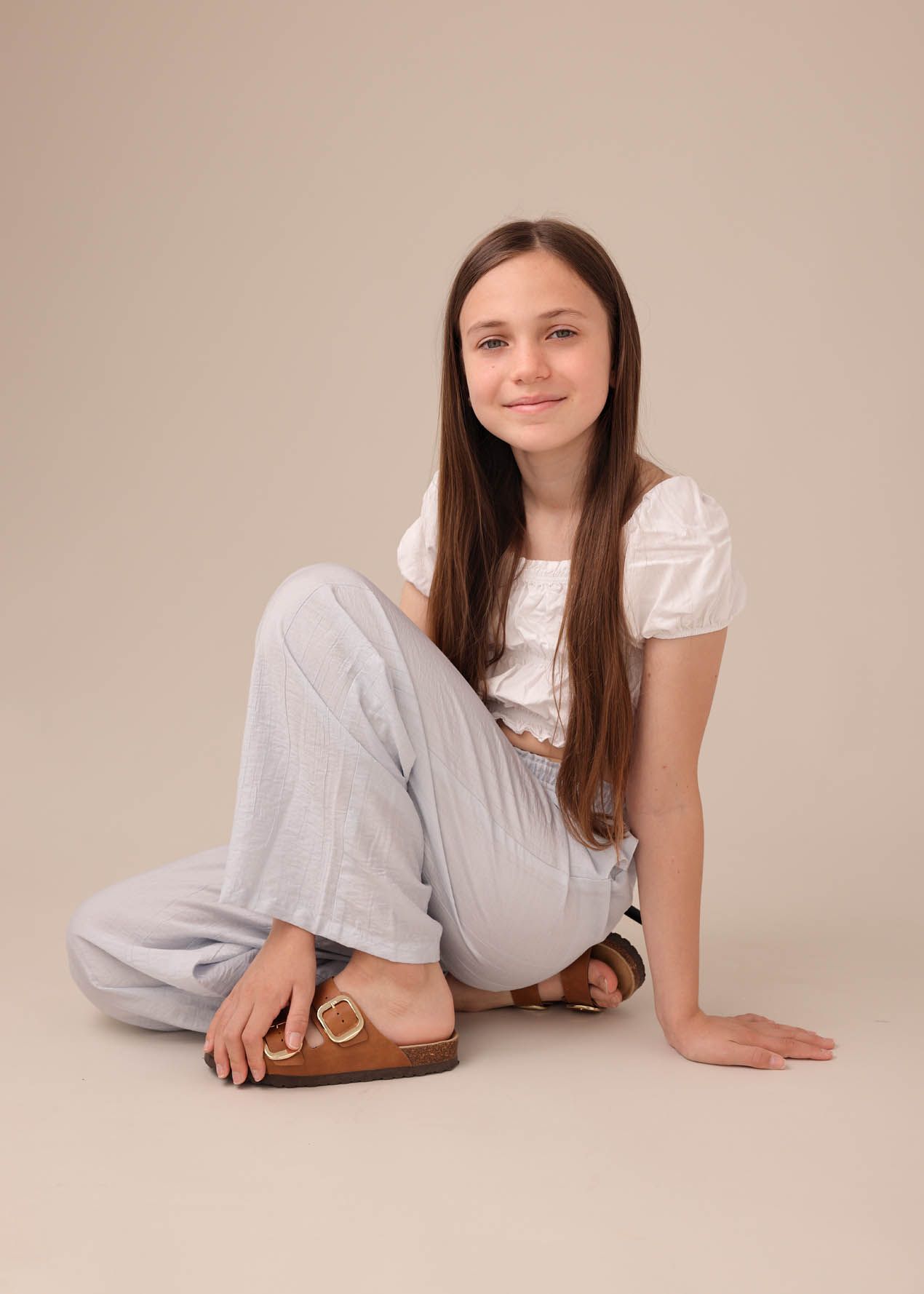 Smiling girl sitting in a relaxed pose in a white top and blue trousers during a summery fashion photoshoot at Abigail Stewart Photography s