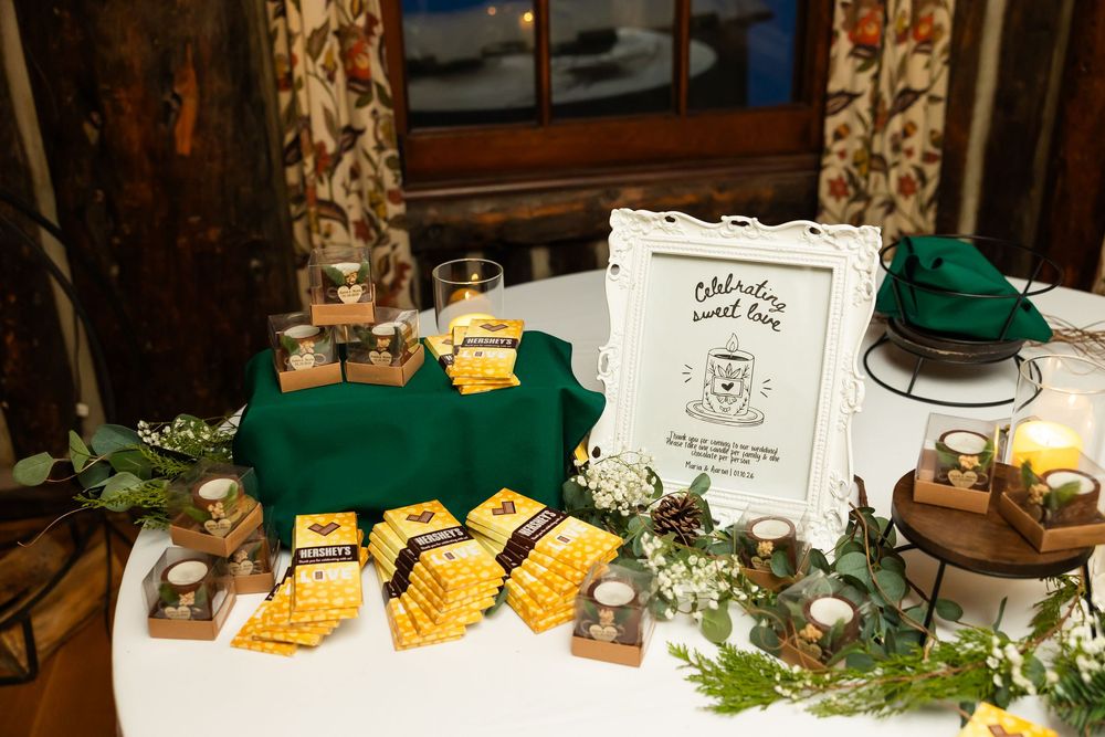 Elegant wedding dessert table with yellow waffle cookies, candles, greenery, and a framed sign on a green tablecloth.