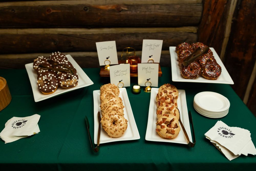 A dessert table with chocolate brownies, cookies, and pastries on white platters with a green tablecloth.