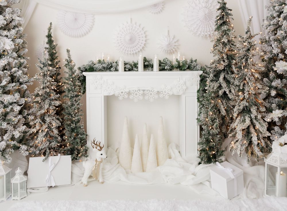 White winter wonderland scene with frosted Christmas trees, decorative fireplace, reindeer figurine, and gift boxes.