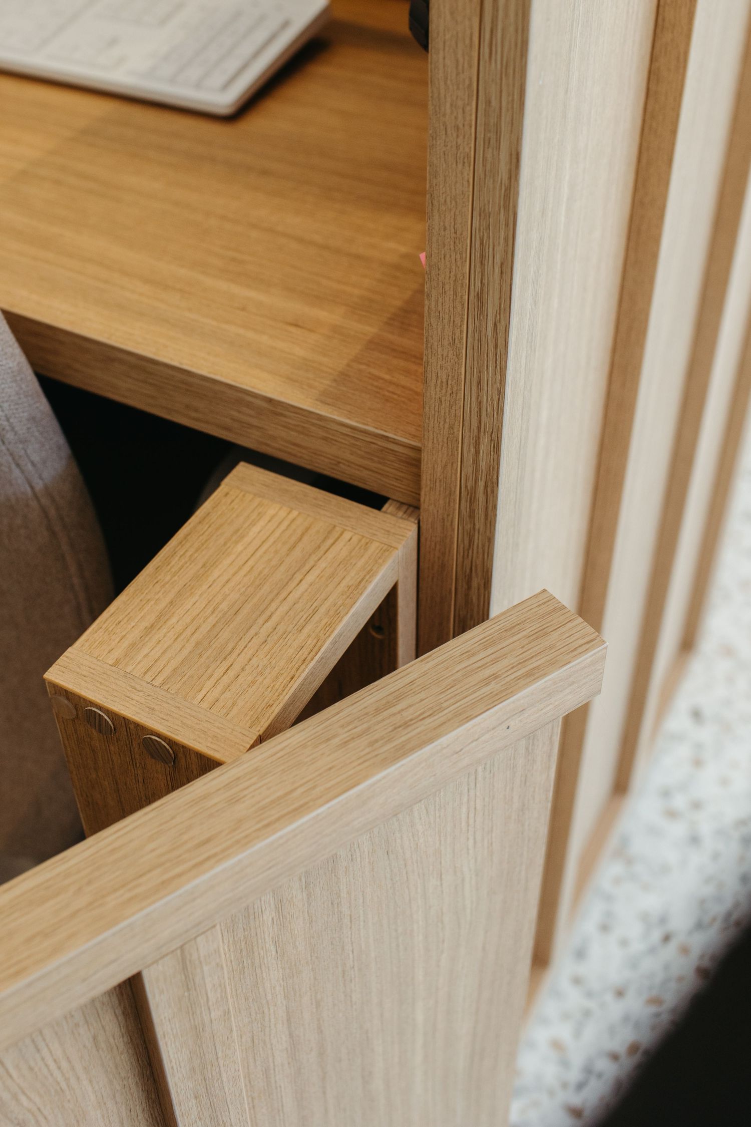 Close-up of a light oak wood furniture piece featuring clean joinery, shelving, and slatted panel details.