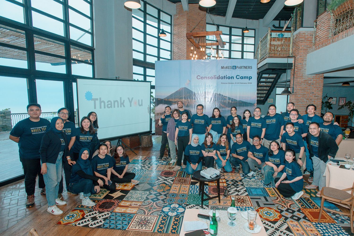 Group photo of team members at a Consolidation Camp event with a Thank You banner displayed on screen.