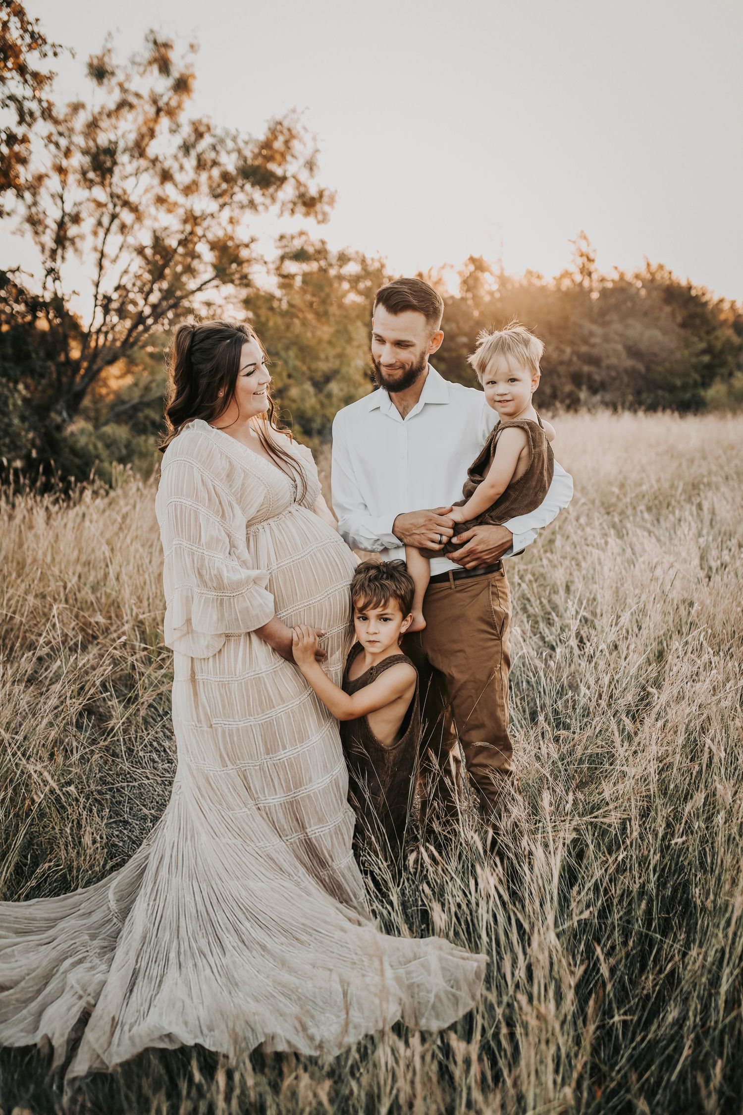 Golden sunset maternity session with a family dressed in warm cream and brown tones