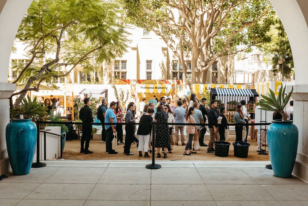 Crowd of guests gathered under arched entrance at an outdoor wedding cocktail reception.