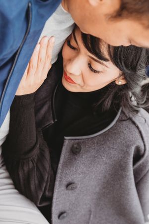Intimate close-up of gentle embrace with grey coat and black sweater detail.