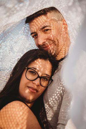 A creative portrait with lace pattern shadows cast over a couple's faces.