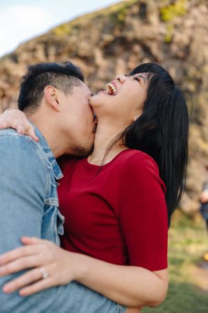 Joyful and playful romantic moment captured outdoors against rocky backdrop.