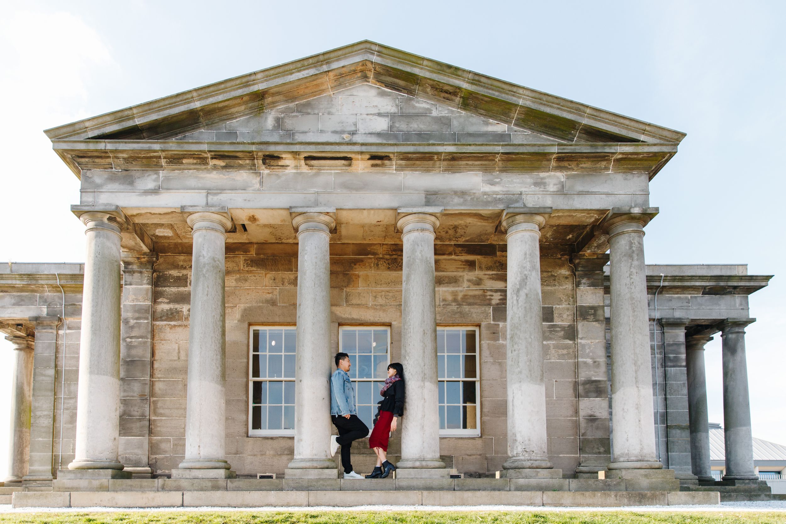 Couple posing in front of a grand neoclassical building with columns and pediment.