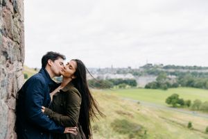 A tender moment between a couple against a scenic countryside backdrop.