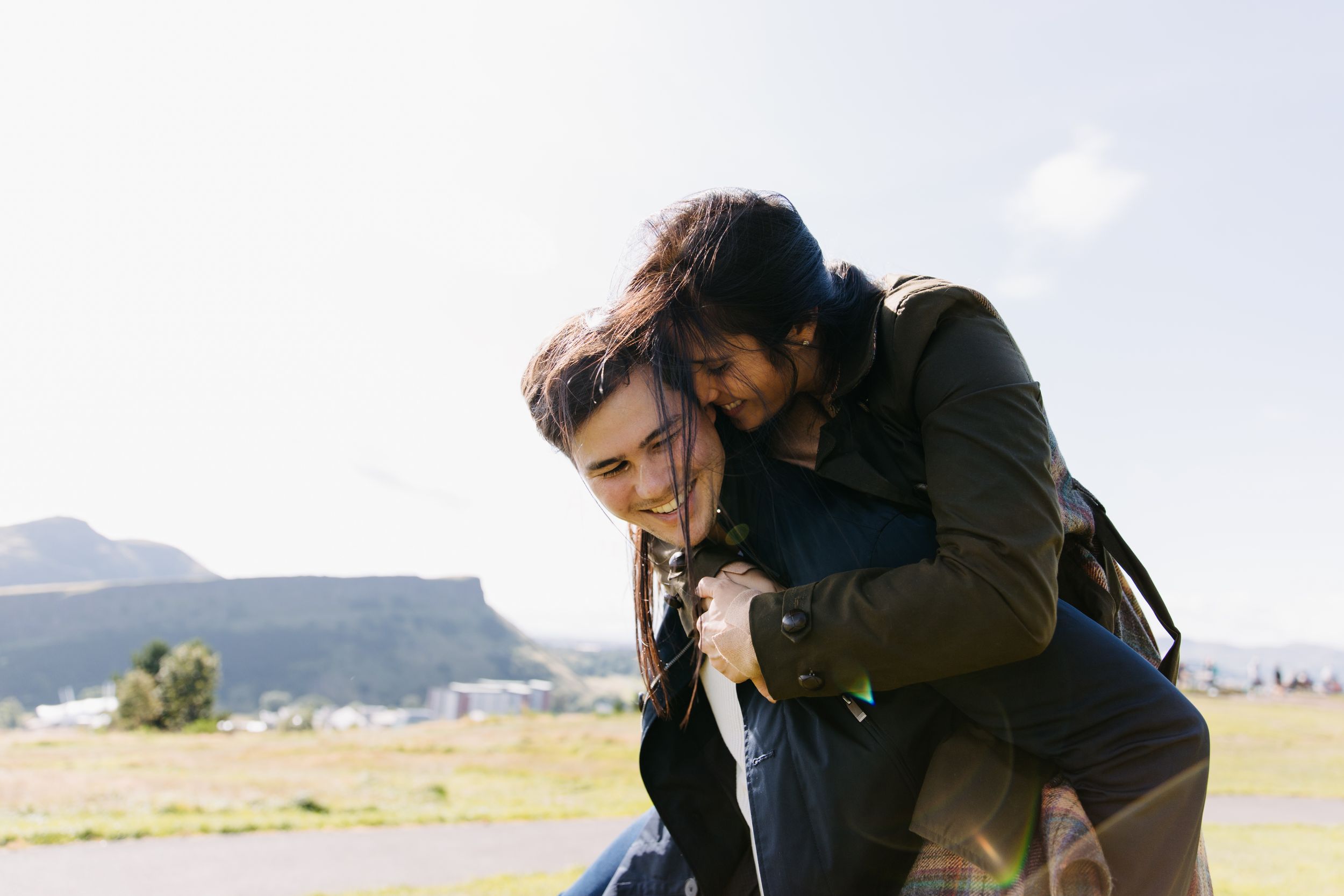 A playful piggyback ride moment captured in front of mountain scenery.