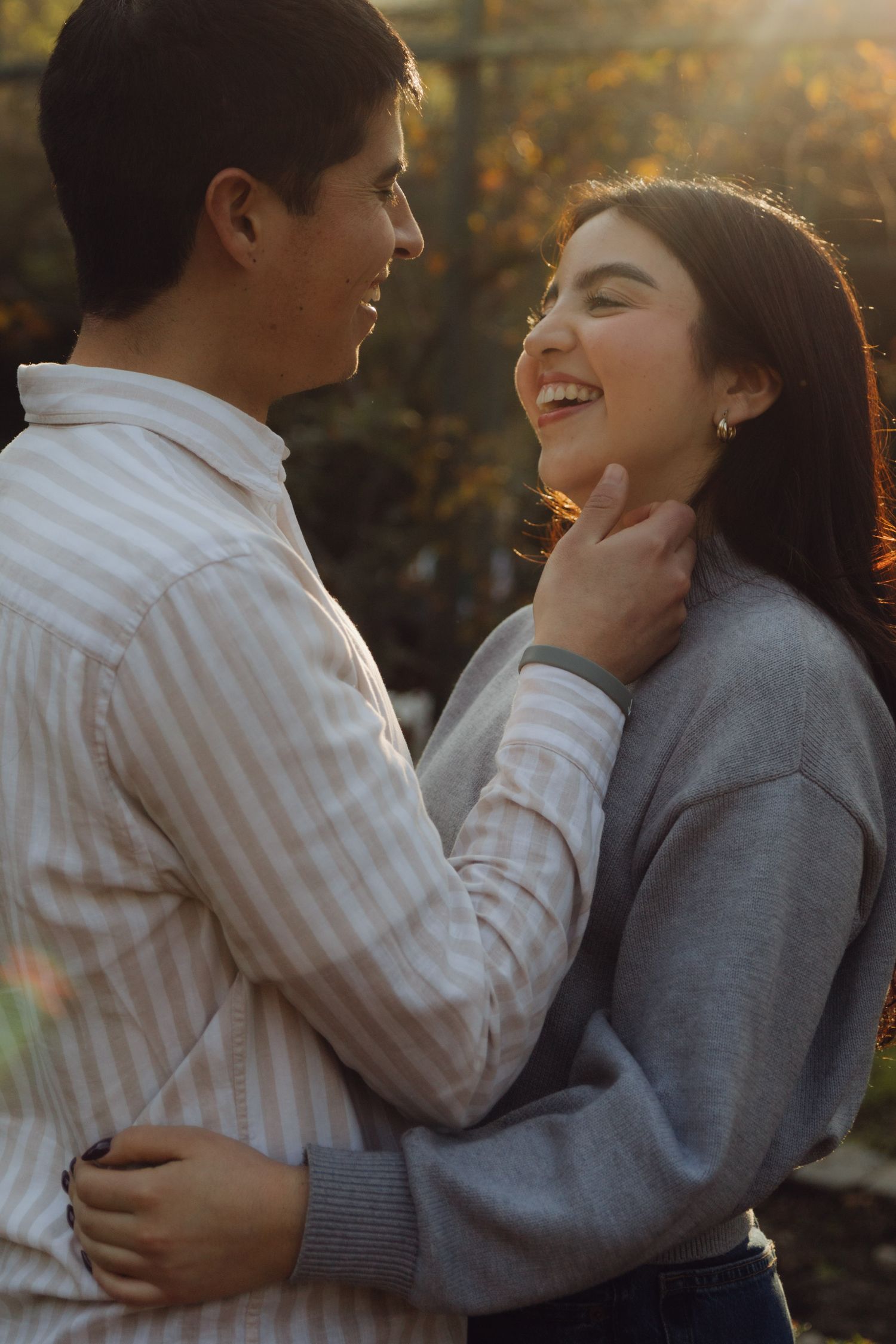 Happy couple sharing a joyful moment together outdoors, bathed in warm golden sunset light.