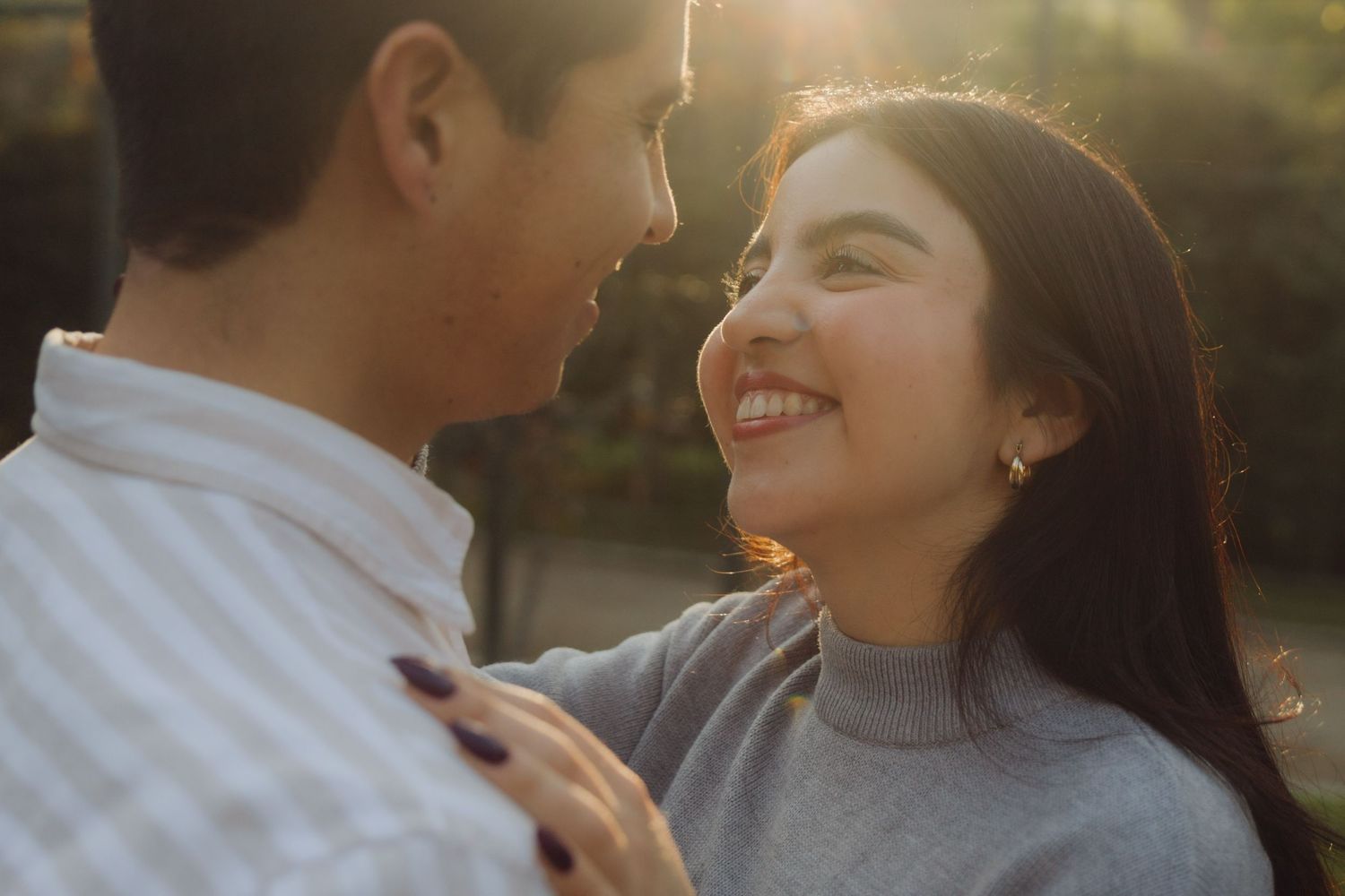 Close-up of a smiling young woman looking up at her partner in beautiful warm golden sunlight.