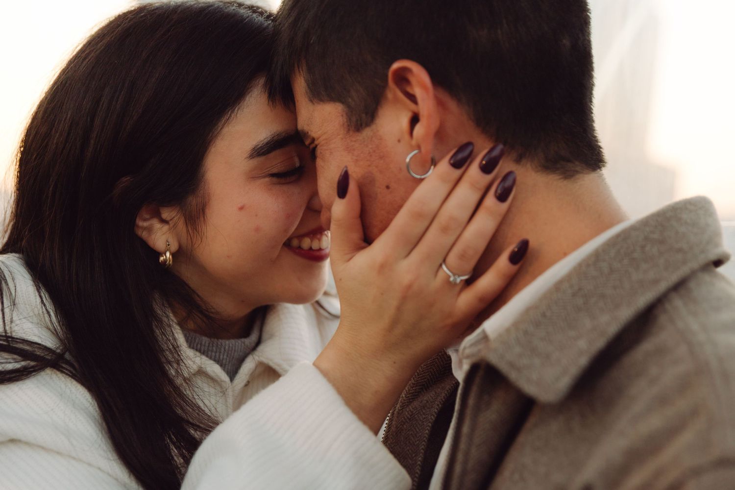Smiling woman tenderly touching mans face during romantic close-up moment together.