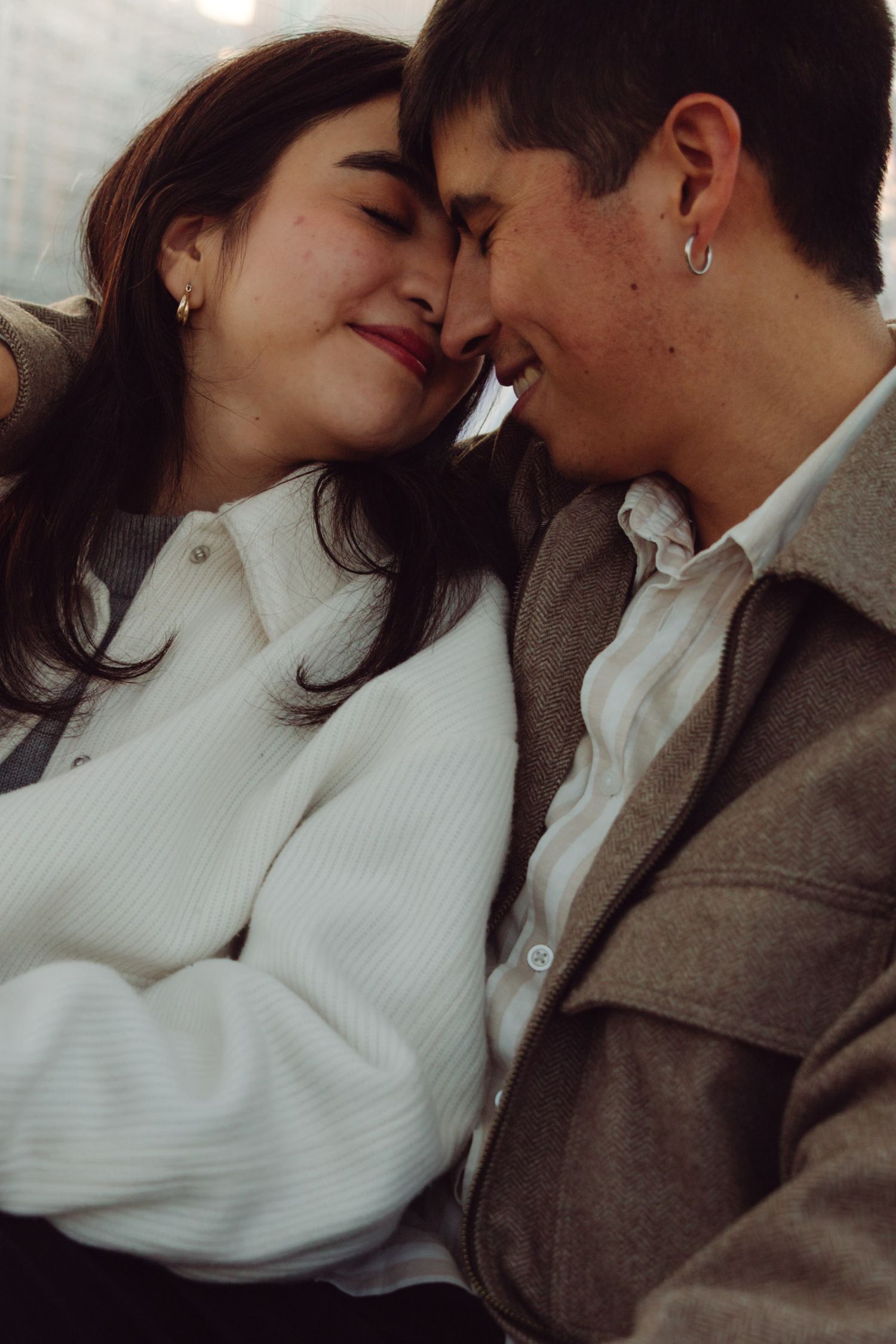 Engaged couple touching foreheads tenderly, sharing a sweet romantic close moment.