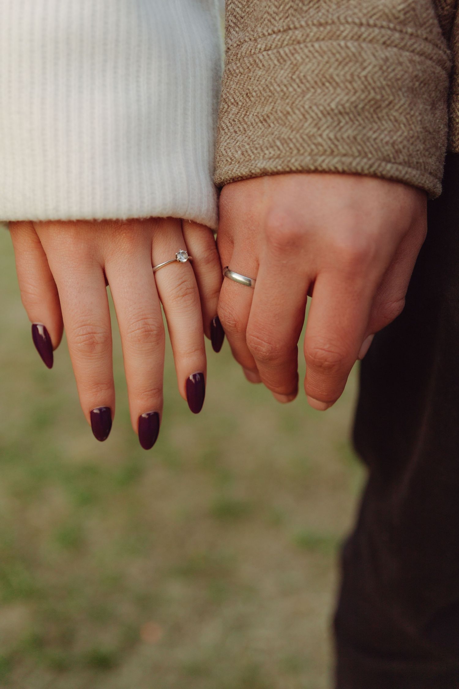 Close-up of engaged couples hands showing diamond and band engagement rings.